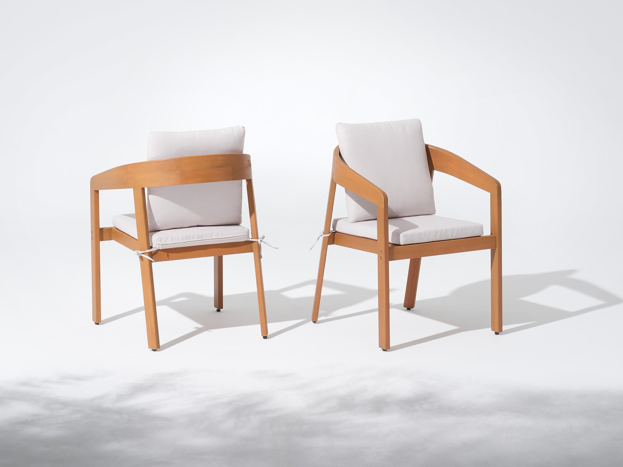Two wooden chairs with white cushions on a white background, Drift Wooden Outdoor Dining Chairs With Curved Backrest - Sunsitt’s Modern Premium Outdoor Furniture